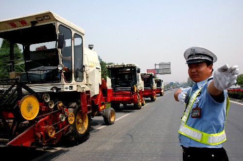 5月22日,河南济源交警在为“麦客”指引道路。 5月中旬以来,众多南下参加麦收的“麦客”途经河南省济源市。当地交警在为“麦客”搞好服务的同时,特别提醒“麦客”注意交通安全。 新华社发(苗秋闹 摄)