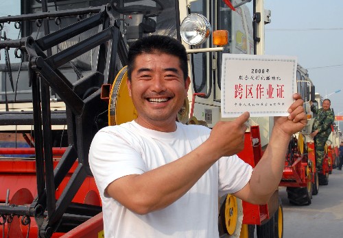 5月22日,山东省枣庄市“三夏”农机跨区作业户郭飞拿着“跨区作业证”喜笑颜开。 当日,山东省枣庄市“三夏”农机跨区作业出征仪式在峄城区举行,200余台联合收割机踏上今年跨区作业的征程。 新华社发(孙启路 摄)