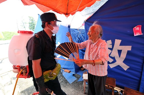 这是防疫队员在都江堰玉堂镇外滩社区与一位老人交谈(7月1日摄)。 自汶川大地震发生以来,国家质检总局组织的由380余人组成的卫生防疫队一直工作在抗震救灾第一线,目前已处理灾区卫生防疫面积达3448万平方米。 新华社记者何俊昌摄