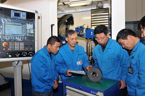 这是秦川机床工具集团有限公司研究院副院长王俊岭(左二)和院里技术人员研究分析磨削误差产生的原因和消除方法(12月12日摄)。新华社记者 何俊昌 摄