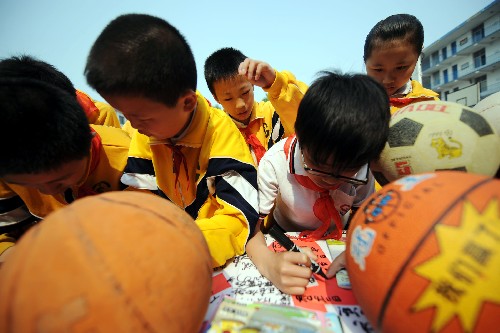 5月19日,湖南长沙曙光小学学生向四川地震灾区捐赠书籍和体育用品,并在横幅上签名。 新华社记者 赵众志 摄
