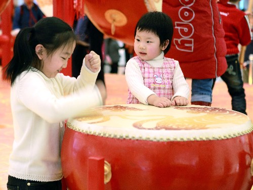2月14日,两名小朋友在北京王府井东方新天地商场里敲鼓,庆祝新年。 春节假期,各地的孩子们在家长的陪伴下纷纷走出家门,参加各种活动,在浓浓的亲情中欢度新春。 新华社发(罗伟 摄)