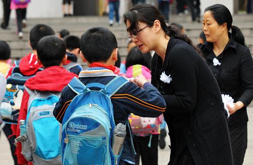 3月24日,福建南平实验小学教师在学校门口向学生发放小白花。新华社记者 魏培全 摄