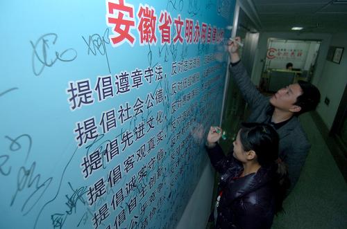 3月25日,合肥论坛网络社区(即合肥热线)的两名工作人员在《文明办网自律公约》海报上签名。新华社记者 郭晨 摄