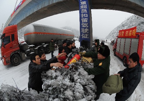 2月2日,湖南消防总队郴州消防支队的官兵正在为被堵油罐车辆的司机发放灭火器。 新华社记者 陈树根 摄