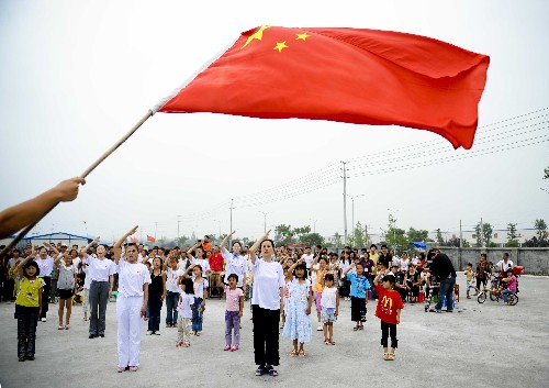 图为:6月21日,中国舞蹈家协会的演员与灾区都江堰市勤俭人家安置点的孩子们一起向五星红旗敬礼。 新华社记者 刘杰摄