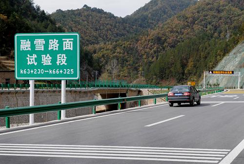 10月26日,汽车行驶在沪陕高速公路秦岭隧道出口处“融雪路面试验段”。该路段首次在国内引进日本的盐化物融雪剂,在秦岭两侧长大下坡路段铺筑了融雪路面,确保特殊环境下的行车安全。 新华社记者 陶明 摄