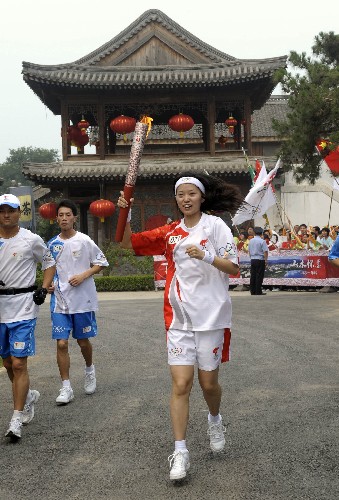 8月7日,火炬手惠尚懿手持火炬传递。当日,北京奥运圣火在北京市传递。 新华社记者戚恒摄