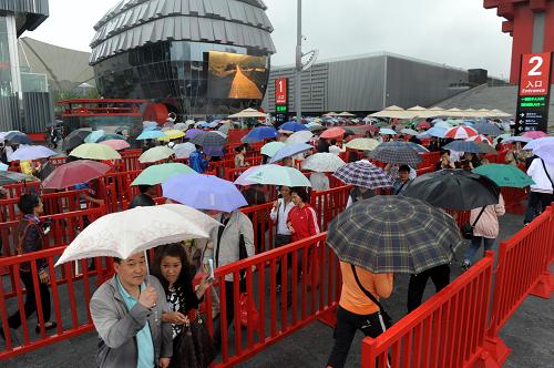 世博雨游 5月5日,游客在中国馆前排队准备入馆参观。 当日,上海迎来世博会正式开幕以来首个降雨天气,在连续多个“高温天”之后,世博园区内的游客感觉凉爽了不少。据上海中心气象台消息,上海降雨天气将持续,局部地区雨量可达中等程度,风力依然较大,未来3至4天的最高气温将降至24至25摄氏度。 新华社记者李紫恒摄