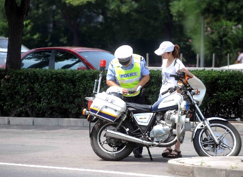 7月20日,一名交警在北京复兴门附近对一名违反单双号限行规定的车主进行处罚。新华社记者 罗晓光 摄