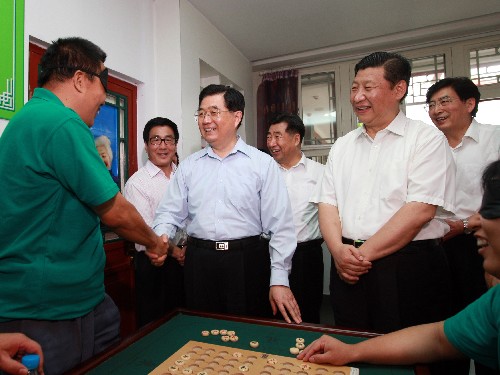 这是胡锦涛在北京市什刹海街道残疾人温馨家园的棋牌室同正在下棋的盲人亲切交谈。 新华社记者鞠鹏摄