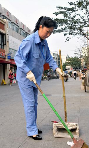 这是上海市普陀区清洁女工陈扣娣用自己发明的“渔网兜”清扫街道(2009年8月26日摄)。在21年的环卫工作中,陈扣娣满怀感情投入最基层的清洁工作。新华社记者 肖春飞 摄