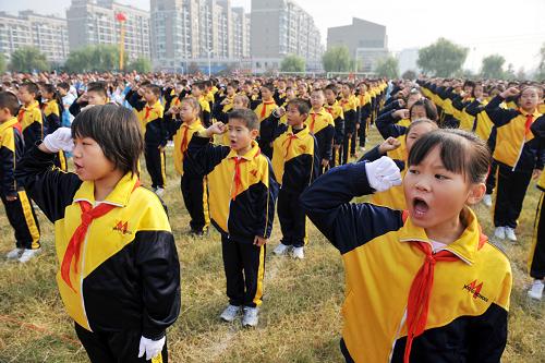10月13日,一名少先队员(右)拉着新队员的手进行结对帮扶交流。 当日,江苏省连云港市墟沟小学举行庆祝中国少年先锋队建队60周年活动。在少先队大队举行的入队仪式上,新队员戴上红领巾,面对少先队队旗宣誓,光荣地加入中国少年先锋队。新华社发(王健民 摄)