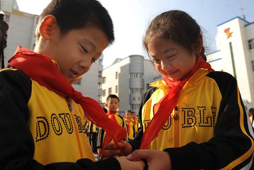 10月13日,乌鲁木齐市实验小学一年级新入队少先队员们正高兴地抚摸红领巾。当日是中国少年先锋队建队60周年纪念日,乌鲁木齐市各族少先队员佩戴鲜艳的红领巾共同参加队日活动,一些学校还举行新生入队仪式。新华社记者 王菲 摄