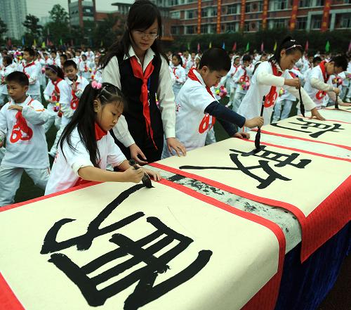 10月13日,少先队员在主题活动中表演书法。当日,“红旗下的誓言”重庆市纪念少先队建队60周年主题活动在兰花小学举行,1000余名师生参加本次活动。新华社记者 周衡义 摄
