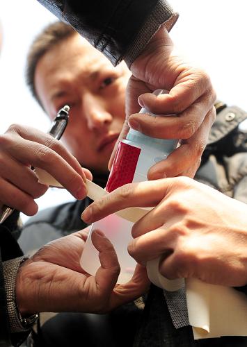 3月6日,救援人员将荧光棒粘贴到装有营养液的瓶上准备送到井下。新华社记者 任军川 摄