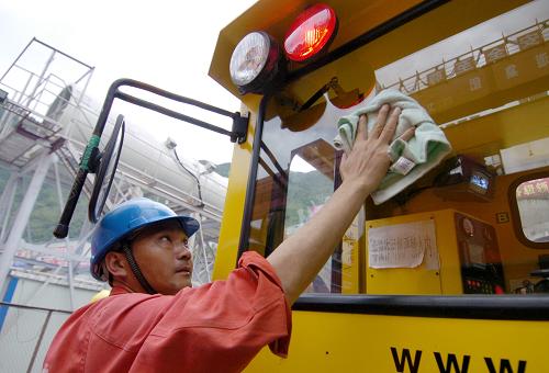 7月3日,在兰渝铁路西秦岭隧道2标的施工现场,施工人员在擦洗轨道车的玻璃。新华社记者 高健钧 摄