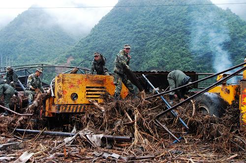 武警陇南森林支队官兵正在清理被洪水淤积物淹没的工程车(8月20日摄)。新华社记者 吴明轩 摄