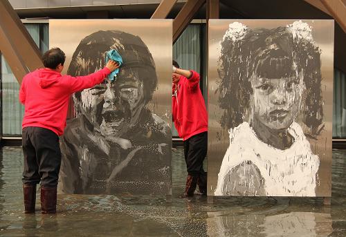 11月1日,工作人员在擦拭法国馆外严培明的黑白油画作品。2010年上海世博会闭幕后,园区熙熙攘攘的景象一天之内消失了,偶尔有工作人员在空旷的场馆间穿梭。世博园还留着几千万人活动过的痕迹:倒在地上的遮阳伞,曾经在酷热的夏天为数千万人遮光挡雨;依然咝咝响着的扬声器,在184天中不间断地广播寻人启事……随着各国展品的撤出,大部分场馆也将陆续拆除,2010年上海世博园渐行渐远。新华社记者 邢广利摄