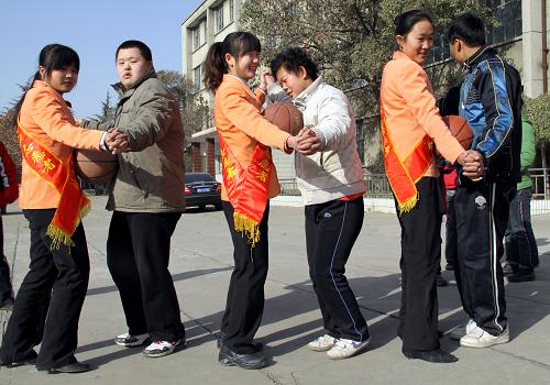 12月3日,在枣庄市市中区特殊教育中心,志愿者与智障学生一起做“牵手运球”游戏。新华社发(孙中喆 摄)