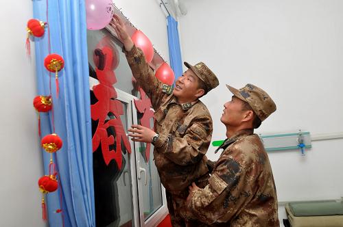 1月29日,5390前哨战士将自己制作的春节装饰品挂在墙上。喀喇昆仑山腹地的天文点边防连5390前哨官兵在完成边防执勤任务之余,自己动手写对联、贴窗花、拉彩旗、挂灯笼,把营区和寝室打扮得喜气洋洋,以高原边防军人特有的方式迎接兔年春节的到来。5390前哨以驻地海拔高度命名,这里年平均气温零度以下,空气中的含氧量不足平原地区一半。官兵常年在异常恶劣的自然环境中战严寒、斗缺氧,每年都圆满完成上级赋予的各项任务。新华社发(向文军 摄)