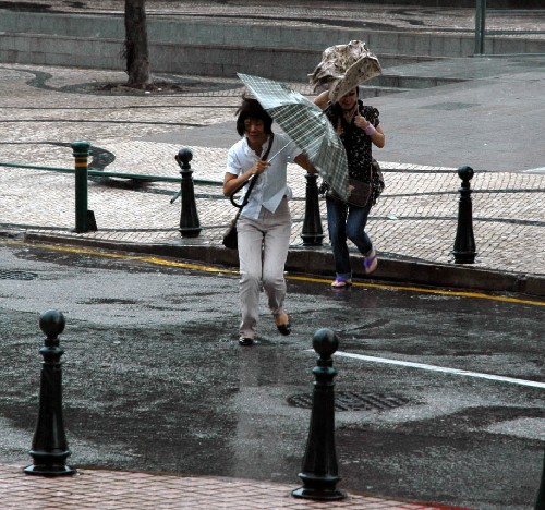 6月25日,市民顶风冒雨前行。当日清晨,2008年第6号强热带风暴“风神”掠过澳门。受狂风暴雨影响,澳门中小学及幼儿园暂时停课,部分航班不能正常起降,往来澳门与香港间的客轮全面停航,穿梭于港澳之间的直升机停飞。 新华社记者刘卫国摄