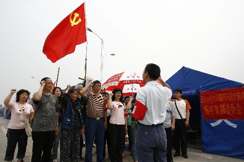 2008年5月23日,党员在四川什邡市60米大街第四段受灾群众安置点临时党支部成立仪式上宣誓。这个24人的临时党支部大多是受灾的普通党员,年龄最大的已经85岁,他们的任务是带领受灾群众抗灾自救。 新华社记者朱炜摄