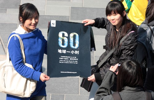 3月28日,两名网友拿着“地球一小时”的活动海报呼吁人们关爱地球。 当天,一些网友自发组织在北京三里屯举行“百人大定格”活动,以定格3至5分钟的形式支持“地球一小时”活动。 新华社发(吴长青 摄)