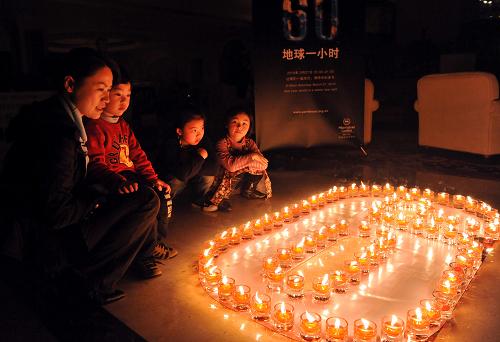 3月27日,一名家长在烛光前为孩子讲解环保的意义。 当日,广西桂林市许多宾馆和消费场所熄灯一小时响应世界自然基金会发起的“地球一小时”熄灯环保活动。 新华社记者 陈瑞华 摄