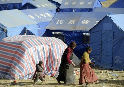 4月26日,在玉树县结古镇扎西大同村,藏族群众走过防震帐篷。 当日,青海省副省长张光荣在国务院新闻办举行的新闻发布会上介绍,截至4月25日17时,地震灾区已经发放帐篷59093顶,棉被207959套,棉衣117027件,食品及饮用水1670吨,火炉子13000个,燃煤1520吨,基本保证群众有饭吃、有干净水喝、有帐篷住。下一步将坚持一手抓有序救灾、一手抓灾后重建,把妥善安置受灾群众生活、全面恢复正常秩序和灾后重建放在更加突出的位置。 新华社记者 郭磊 摄