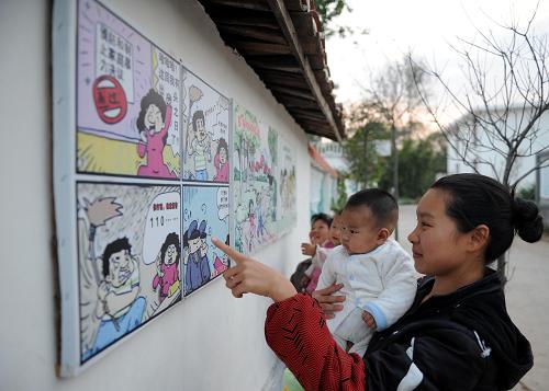 兴国县长冈乡塘石村一对母子在观看围墙上张贴的文明宣传漫画(11月19日摄)。 近年来,在新农村建设过程中,江西革命老区兴国县长冈乡塘石村结合当地红色文化,依托“将军村”“模范村”“博士村”等资源优势,兴建起塘石村史馆、将军亭、博士长廊、模范广场等,让文化娱乐中心、文化广场、图书超市和农家书屋等一批新事物走进农村社区,极大地丰富了农民精神生活。目前,兴国县以集中投入、整体推进的方法,启动联村整片建设点260个,建成新农村建设点2134个,受益农户达38.9万人,覆盖了全县所有行政村和71%的自然村,实现了“走平坦路、喝干净水、上卫生厕、住整洁房、用洁净能、居优美村”的目标。 新华社记者 周科 摄