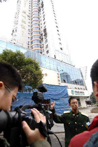 12月13日,一名警官在温富大厦楼下向新闻媒体介绍灭火情况。