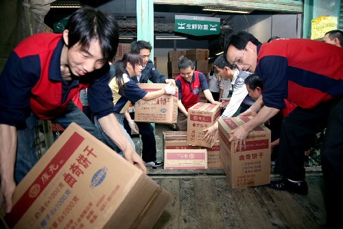 5月17日,贵州救灾志愿者将救灾生活物资搬运上车。 当日,贵州省政府将价值100多万元的矿泉水、火腿肠、饼干等灾区急需生活物资,紧急运往四川地震灾区。 新华社发(何波涛 摄)
