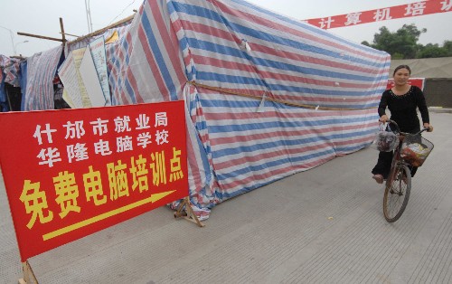 6月16日,一名群众骑车驶过什邡市方亭镇安置点的帐篷电脑培训学校。