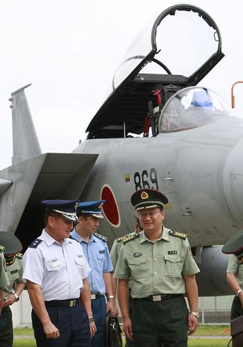 9月4日,在日本东京北部的百里基地,日本航空自卫队第七航空团兼百里基地司令荒木淳一少将(前左一)陪同到访的中国人民解放军中青年军官研修团团长、中国国防部外事办公室政治部主任吕让全(前右一)大校参观F-15战斗机。新华社记者任正来摄