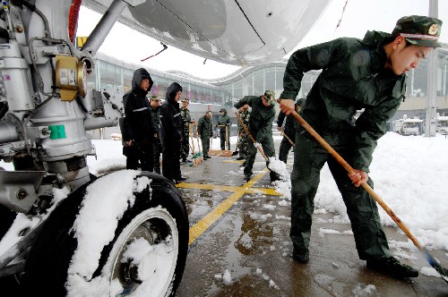 2月2日,浙江公安边防总队杭州边检站的战士们在飞机下除雪。杭州连日暴雪,萧山国际机场的积雪达到近30厘米厚,所有航班取消,整个机场处于关闭状态。杭州边检站组织数十名官兵到机坪线上冒雪清扫机场跑道,力争尽快恢复口岸畅通。 新华社记者 黄深钢 摄