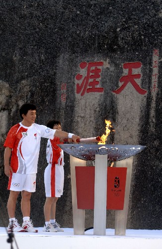 5月4日,最后一棒火炬手成龙(左)和蒲慧芳在天涯海角共同点燃圣火盆。当日,北京奥运会圣火传递活动在海南三亚举行。 新华社记者 赵颖全 摄