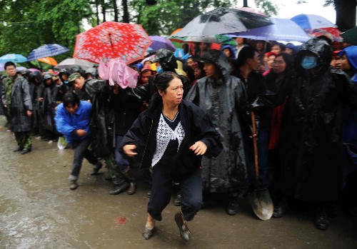 5月13日,一名等待孩子消息的家长看到一名遇难学生的遗体被抬出后,奋力向前冲去。当天,救援人员继续在四川都江堰市聚源镇聚源中学冒雨进行救援工作,虽然地震造成大量伤亡,但仍有迹象表明废墟中有幸存者。 新华社记者 王建华 摄