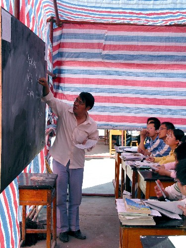 5月16日,陇南市一中教师在帐篷教室内授课。当日,受汶川地震严重影响的甘肃省陇南市的高三年级学生在帐篷中复课。与此同时,陇南市的中小学也在抓紧搭建简易帐篷,为全面复课做好准备。 新华社记者 连振祥 摄