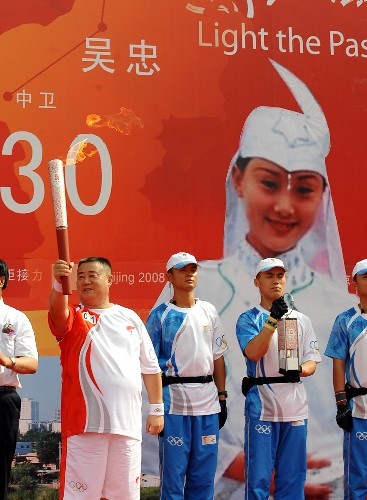 6月30日,第一棒火炬手霍庆华在起跑仪式上展示火炬。当日,北京奥运圣火在宁夏吴忠传递。 新华社记者 刘泉龙 摄