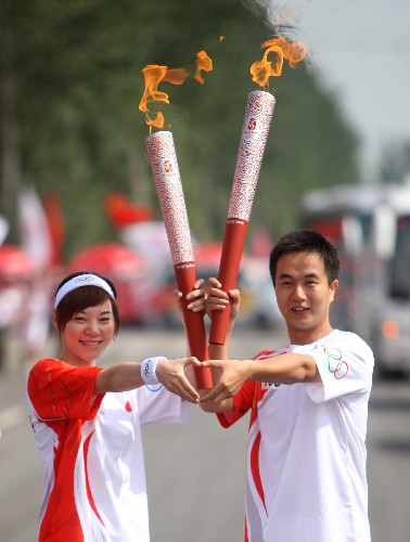 6月30日,火炬手郝伟(右)与下一棒火炬手王彬宸交接。当日,北京奥运圣火在宁夏吴忠传递。 新华社记者 邢广利 摄