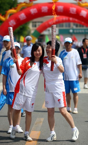 6月30日,火炬手谭兴玲(右)与下一棒火炬手骆佳交接。当日,北京奥运圣火在宁夏吴忠传递。 新华社记者 邢广利 摄