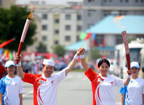 6月30日,火炬手王春荣(右二)与下一棒火炬手马全国交接。当日,北京奥运圣火在宁夏吴忠传递。 新华社记者 邢广利 摄