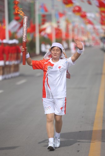 6月30日,火炬手马晓梅手持火炬传递。当日,北京奥运圣火在宁夏吴忠传递。 新华社记者 邢广利 摄