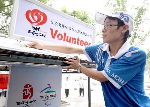 7月1日,一名城市志愿者在北京西城区什刹海站点擦拭刚刚启用的城市志愿者服务站点。 新华社记者 罗晓光 摄