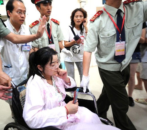 7月3日,左腿高位截肢后的王丽在轮椅上完成了语文考试,被工作人员送出考场。 新华社记者 周衡义 摄