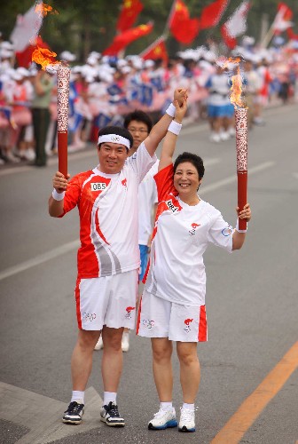 8月8日,火炬手李桂华(右)与下一棒火炬手刘长铭交接后握手致意。当日,北京奥运圣火在北京市传递。 新华社记者 邢广利 摄