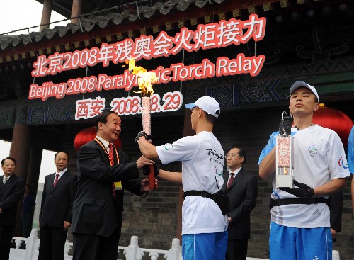 8月29日,北京奥组委执行副主席蒋效愚(前左)接过火炬。当日,北京残奥会圣火在西安进行传递。 新华社记者 金良快 摄