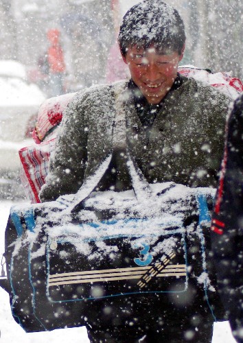 1月26日,乘客冒雪来到巢湖汽车站等车。 新华社发