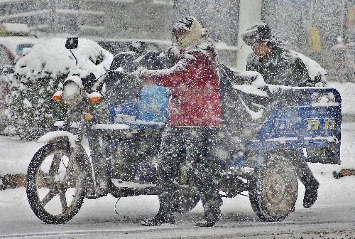 1月26日,市民冒雪推车走在巢湖市长江路上。 新华社发